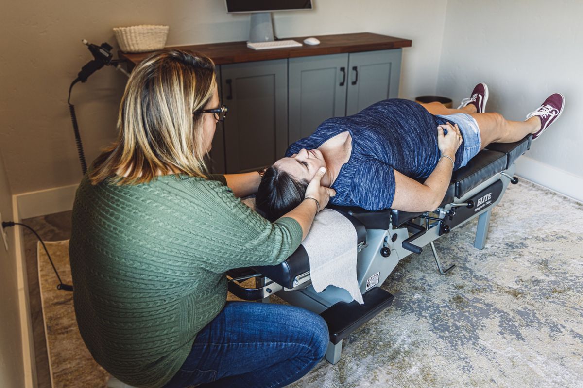A chiropractor adjusting an adult patient lying on an adjusting table