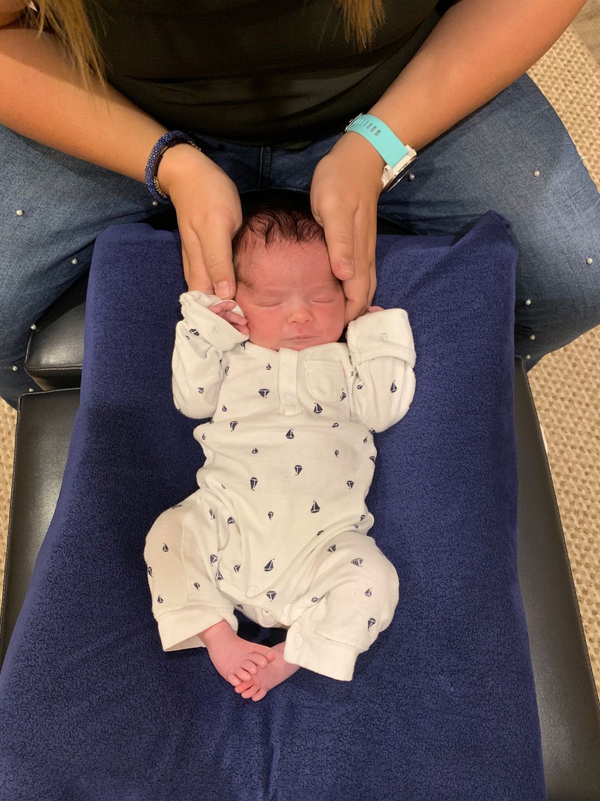 A chiropractor gently cradles the head of a sleeping newborn