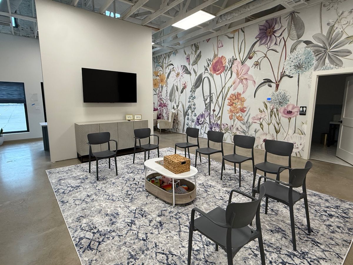 The Vitality waiting room with a basket of toys, rows of chairs and a floral wall mural